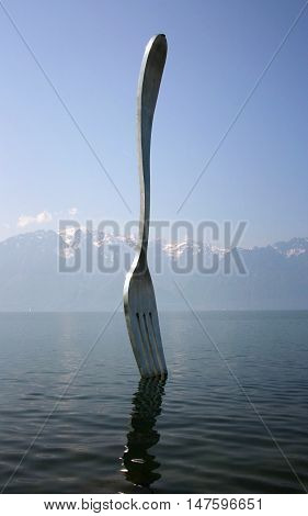 Vevey Switzerland - May 03 2009: Giant steel fork in water of Geneva lake Vevey Switzerland.The fork went up in 1995 to mark the 10th anniversary of the Alimentarium Veveys Food Museum.