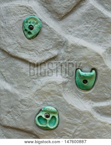 Grungy surface of an artificial rock climbing wall with toe and hand hold studs.
