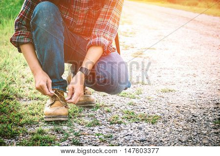 Traveler man hand's tying shoe laces on street traveler and holiday concept vintage tone