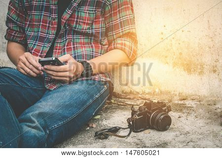 Young Man Using Mobile Phone with old retro camera