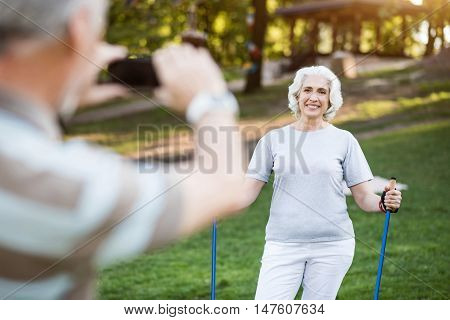 Achieved Husband takes a photo of his attractive elder wife after doing sports in park