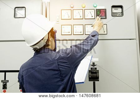 Technician is recording data Voltage or current in control panel of power plants