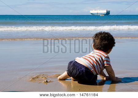 Bebé gateando en la playa y jugando con arena