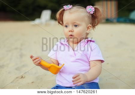 surprised little girl playing in the sand. The concept of childhood and development.