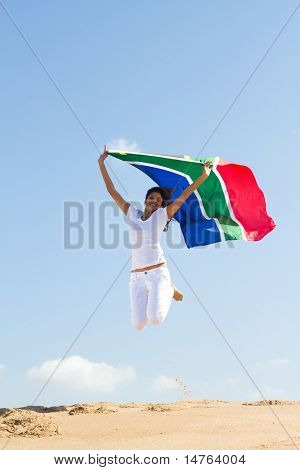 feliz jovem segurando uma bandeira de África do Sul e saltar na praia