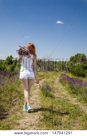 beautiful girl in a field picking flowers