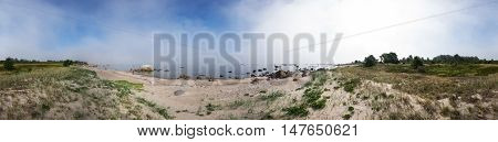 Rocky beach and morning fog in summer. White clouds blue sky and sea mist coast forest seaside natural environment. Shore in Koipsi Island Estonia Europe. 360 degrees panorama.