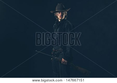Retro 1900 Western Cowboy Standing With Rifle. Young Man. Studio Shot.