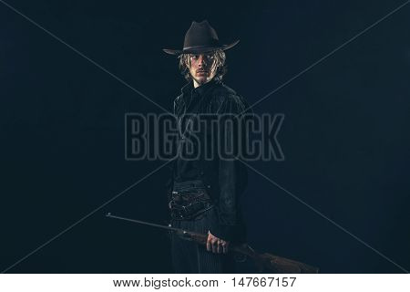 Retro 1900 Western Cowboy Standing With Rifle. Young Man. Studio Shot.