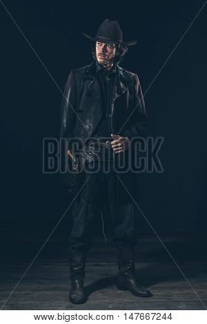 Confident Vintage 1900 Cowboy Showing Revolver. Ready To Shoot. Studio Shot.