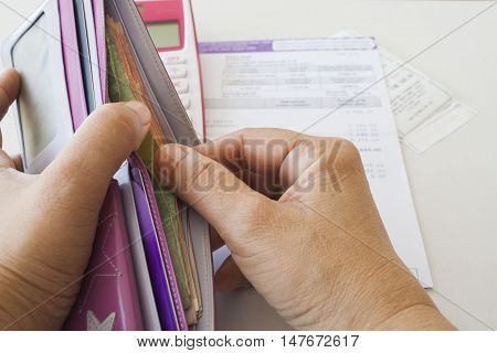 document monthly expense of credit card hand holding purse money and check account