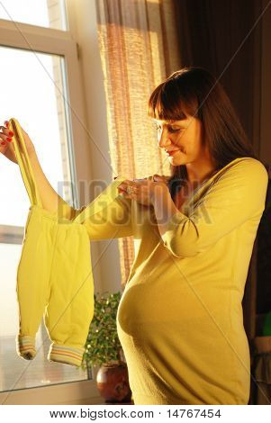 等待第一个孩子的孕妇。阳光从窗口。