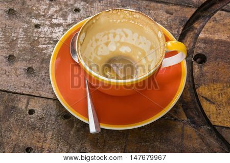 Empty orange mug of coffee latte on vintage wooden table