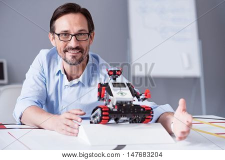 Proud and satisfied. Portrait of a man in glasses smiling while demonstrating new technologies