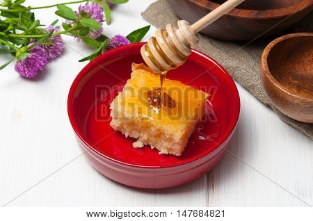 Basbousa - arabian cake with almonds and honey syrup in red bowl on white wooden background