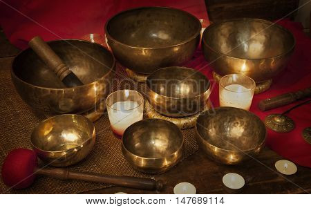 Tibetan singing bowls and bells with burning candles on a red background