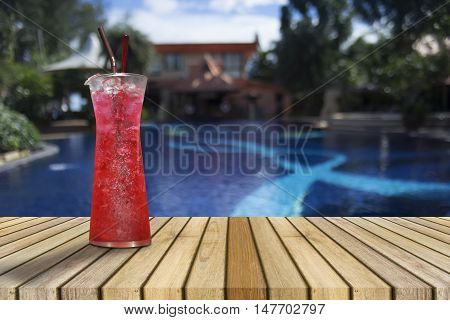 Red soda on Wooden table against of blurred swimming pool. Perspective brown wood over blurred swimming pool,pull your fresh,juice of summer