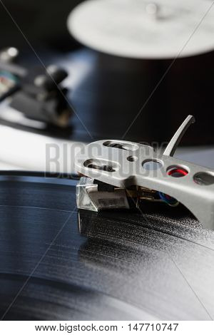 DJ turntable needle playing vinyl recod with music.