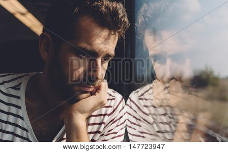 Sad young man looking through the window