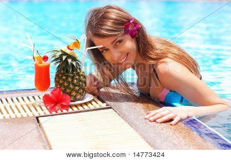 Meisje in het tropische zwembad met cocktail