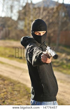 Bewaffneter Mann in schwarzer Maske halten Pistole mit Schalldämpfer