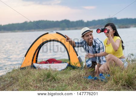 Young Asian couple watching birds in binoculars