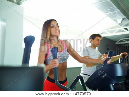 Athletic couple - man and woman doing cardio training program in fitness center