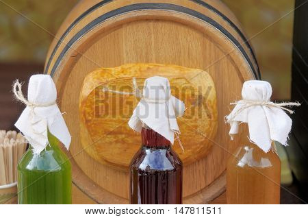 Bottles of homemade liqueurs on the background of wooden barrels