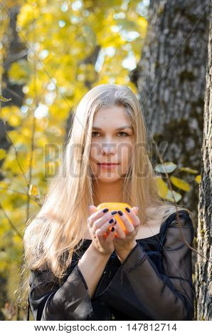 Portrait Of A Young Long-haired Blond Girl In A Black Dress Posing With A Candle