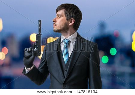 Hitman Or Assassin Holds Pistol With Silencer In Hand At Dusk.