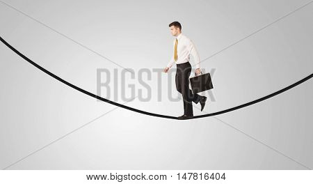 A confident smiling salesman balancing on black wire in clear grey empty space concept