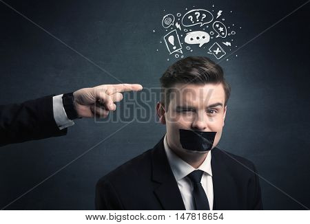Caucasian business hand pointing at stressed male employee with drawn question, explamation marks, talk bubble above his head