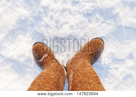 Russian traditional winter footwear - valenki. Winter sunny day top view on feet felted wool boots.