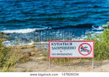 Red no swimming sign posted on the beach