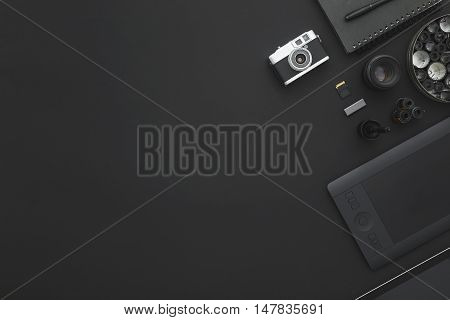 Work space on black table of a creative designer or photographer with laptop tablet camera and other objects of inspiration and copy space. Stylish home studio concept of technology trends.