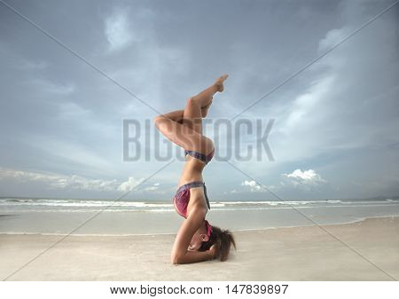Young woman practicing yoga on the beach