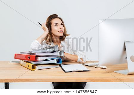 Portrait of concentrated pensive businesswoman thinking about something holding pen isoltaed on the white background