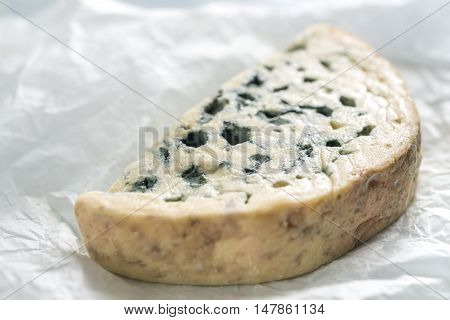 Blue cheese on the white paper close up
