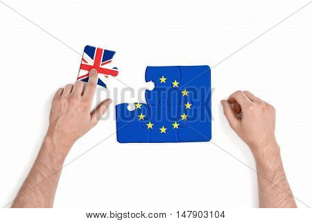 Hand holding piece of jigsaw puzzle with flag of European Union and Great Britain isolated on white background. Brexit puzzle concept. British withdrawal. Significant decision.