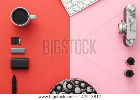 Work space on red table of a creative designer or photographer with laptop tablet camera and other objects of inspiration and copy space. Stylish home studio concept of technology trends. View from above.