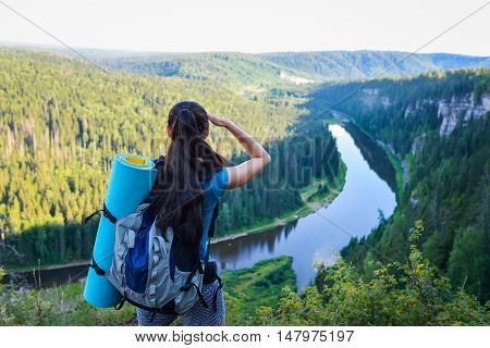 Hiker with backpack standing on a rock and looking to somewhere far away.