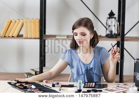 Professional visagiste choosing brush for makeup. Artist tells about importance of each tool for visage making. Beauty, fashion, cosmetics concept