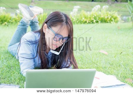 serious businesswoman laydown and work hard on a green grass fields.