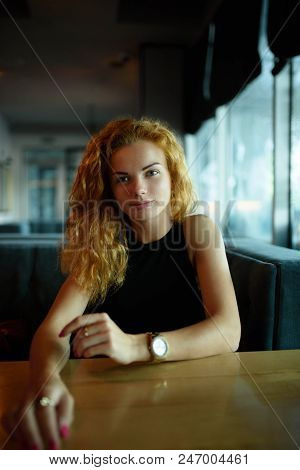 Side View Of Young Woman At Table In Coffee Shop