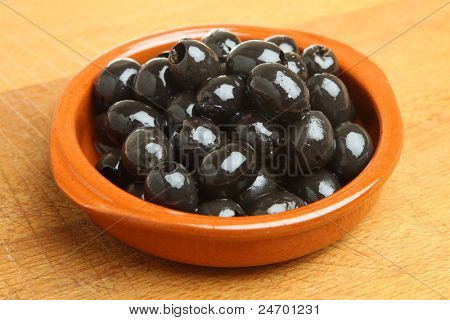 Schwarz entsteint Oliven in Terrakotta-Tapas-Teller oder Cazulea.