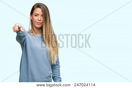 Beautiful young woman wearing sweater and jeans pointing with finger to the camera and to you, hand sign, positive and confident gesture from the front