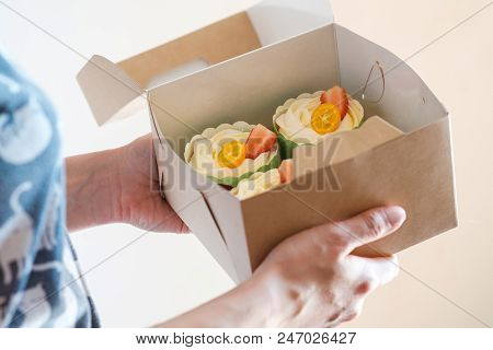 A Bunch Of Cakes Are In The Hands Of A Woman. Strawberries, Kumquat And Whipped Cream. Craft Packagi