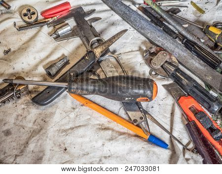 Dirty Set Of Hand Tools On A Home Workbench Close Up. Home Workbench Covered With White Dirty Sheet 