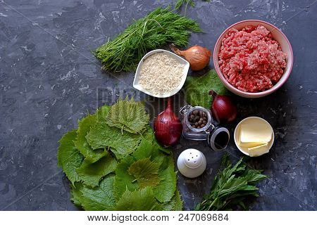 Ingredients For Cooking Dolma / Sarma On A Dark Gray Background. Minced Meat, Fresh Grape Leaves, Bu