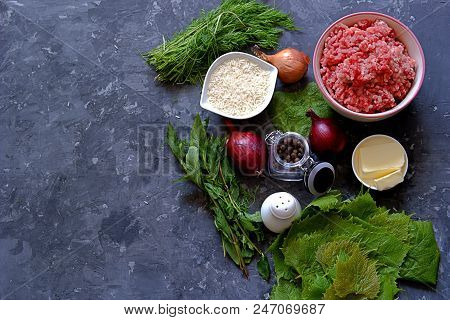 Ingredients For Cooking Dolma / Sarma On A Dark Gray Background. Minced Meat, Fresh Grape Leaves, Bu